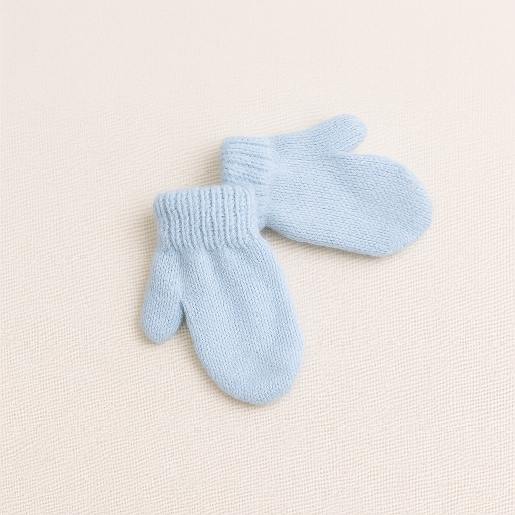 Par de luvas azuis claras de malha para bebé em fundo bege