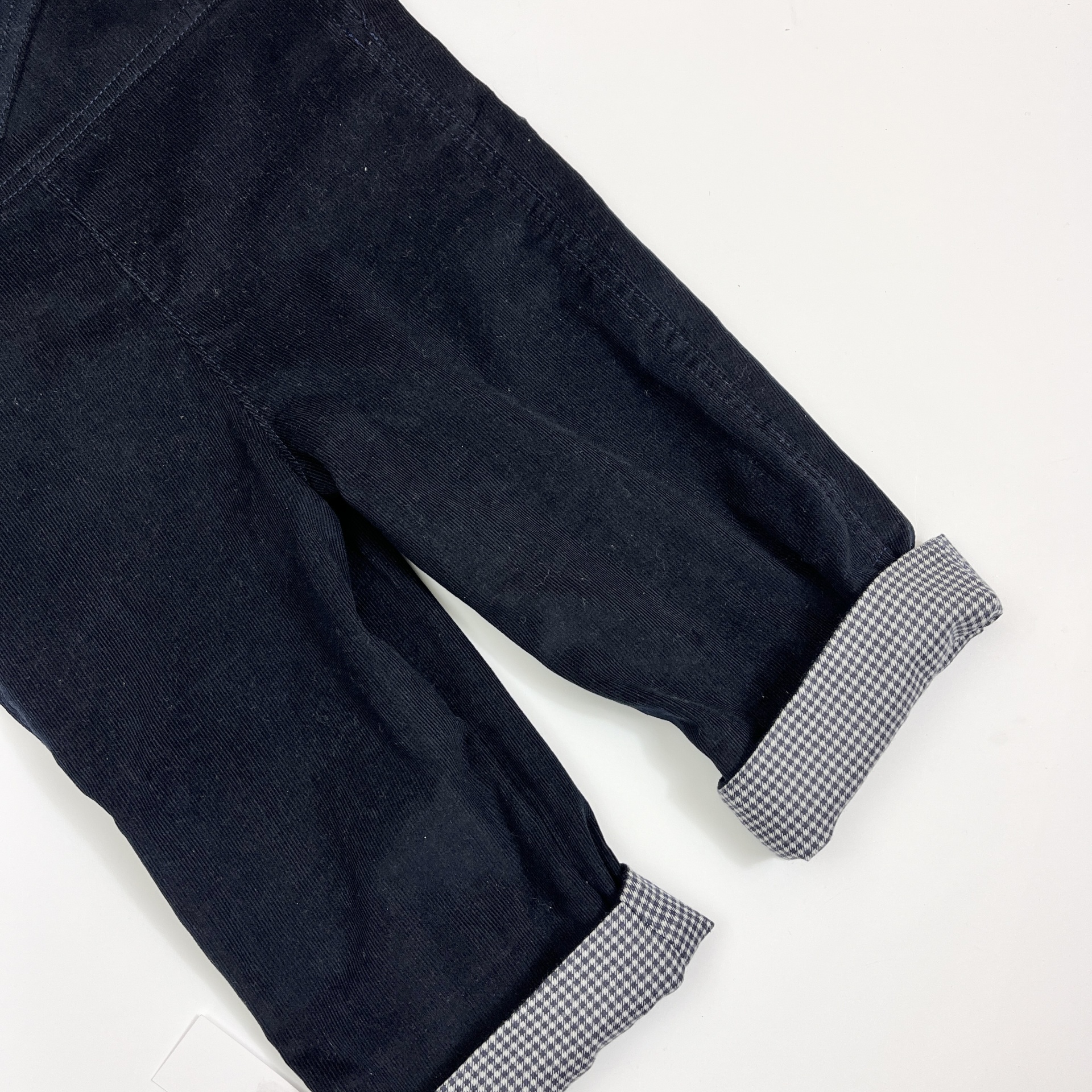 Calças azul escuro com bainha xadrez virada sobre fundo branco