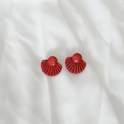 Brincos vermelhos com glitter sobre tecido branco