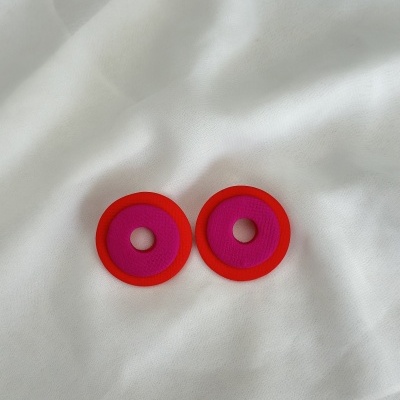 Brincos redondos fúcsia com borda vermelha sobre tecido branco