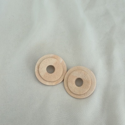 Dois discos redondos de cortiça com furos centrais sobre fundo cinzento claro