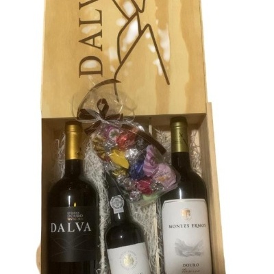 Caixa de madeira com três vinhos e saco de doces coloridos