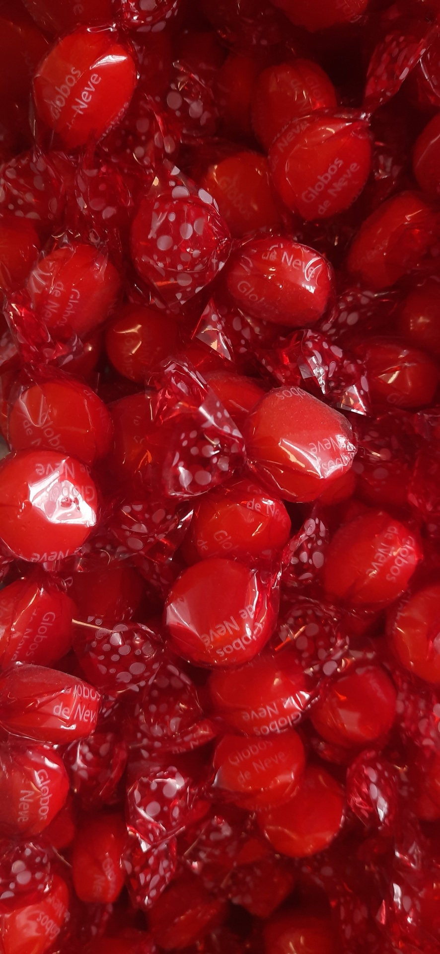 Rebuçados vermelhos embrulhados com padrão de pontos brancos e texto Globos de Neve.