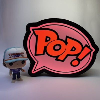Funko Pop com boné e grande placa luminosa rosa com texto POP.