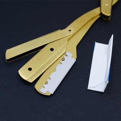 Navalha de barbear dourada com lâmina branca sobre fundo preto