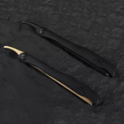 Dois dispositivos para barbear com cabo preto e lâminas de cores diferente em fundo preto texturizado.