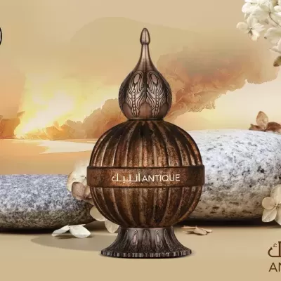 Frasco de perfume marrom envelhecido com tampa pontiaguda e texto ANTIQUE em pedras com flores claras