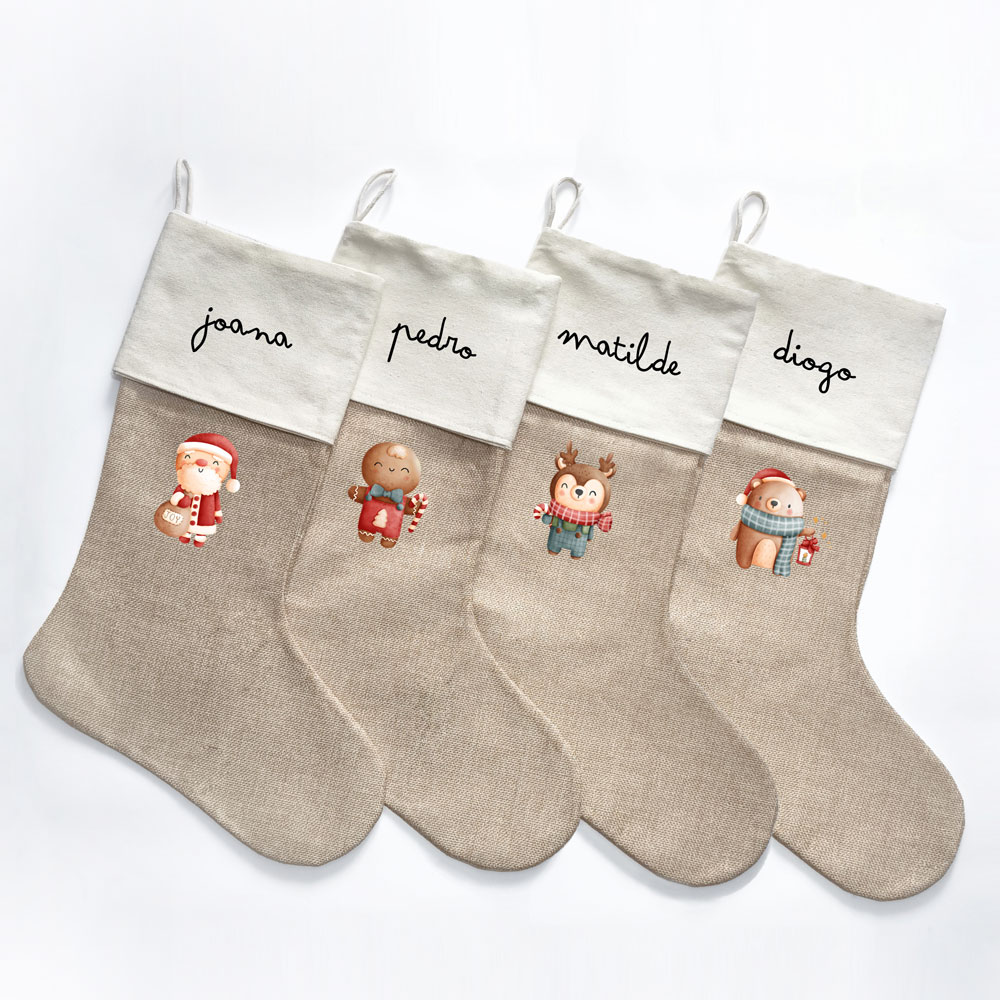 Quatro meias de Natal beje com punhos brancos e nomes escritos, decoradas com personagens natalícios