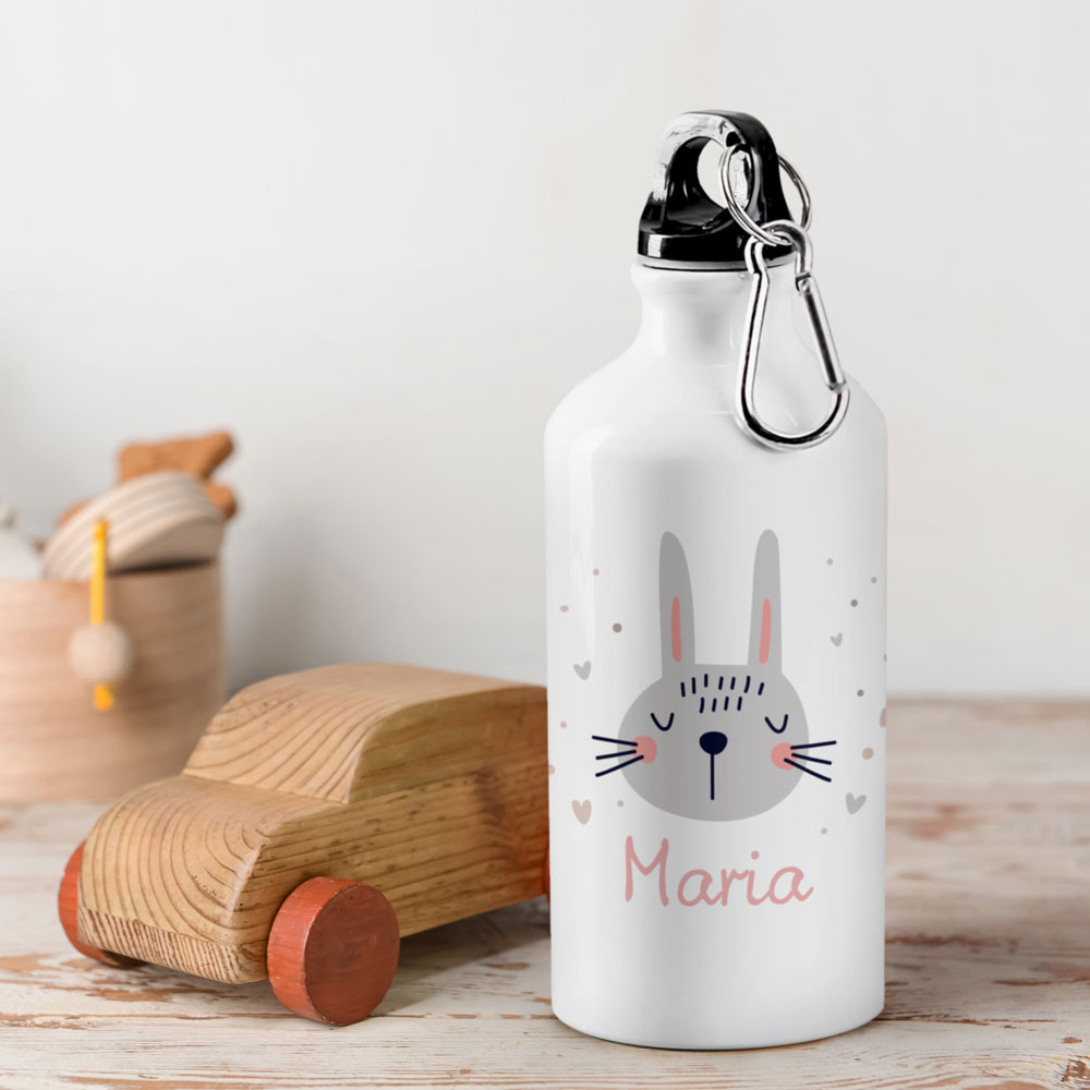 Garrafa térmica branca com desenho de coelho e nome Maria em superfície de madeira