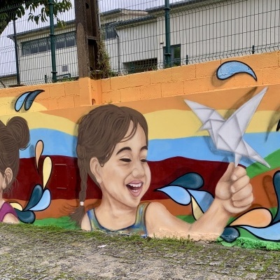Mural de graffiti colorido de crianças felizes com globo e origami numa parede exterior