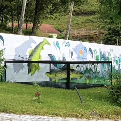 Mural com peixes verdes e flores pintado numa parede exterior