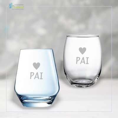Dois copos de vidro com inscrição 'PAI' e símbolo de coração sobre superfície branca