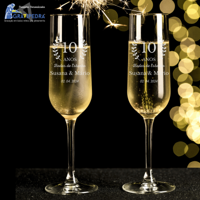 Duas taças de champanhe com gravações comemorativas de 10 anos e fogo de artifício ao fundo