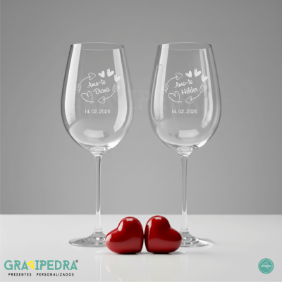 Dois copos de vinho personalizados com texto e desenho de corações, com corações vermelhos em frente.