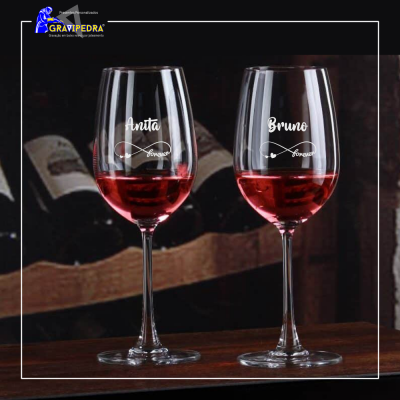 Duas taças de vinho tinto com nomes personalizados Anita e Bruno gravados, sobre superfície de madeira