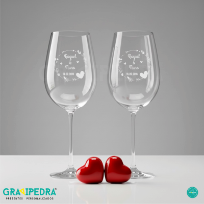 Duas taças de vinho personalizadas com texto branco e dois corações vermelhos em fundo cinza e branco