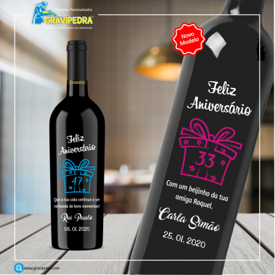 Garrafa de vinho preta com rótulo personalizado de aniversário e texto em azul e outra garrafa de vinho com rótulo rosa em fundo interior