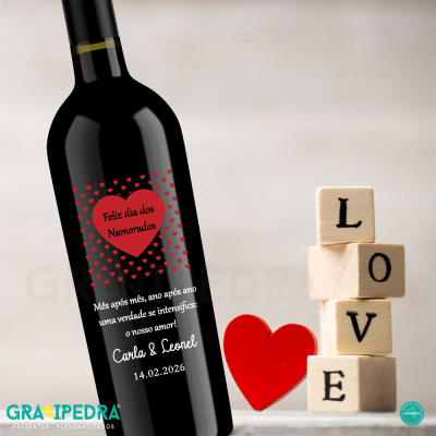 Garrafa de vinho preta com rótulo de dia dos namorados ao lado de cubos formando a palavra LOVE e um coração vermelho.