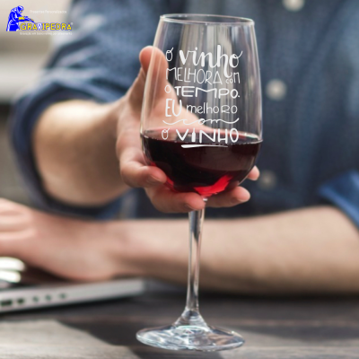 Taça de vinho com texto em branco segurada por mão em mesa com portátil