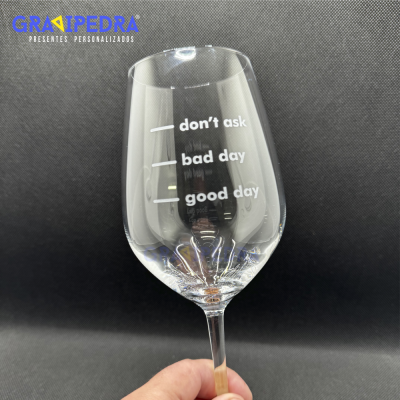 Taça de vidro com frases motivacionais em inglês e logótipo da marca sobre fundo preto