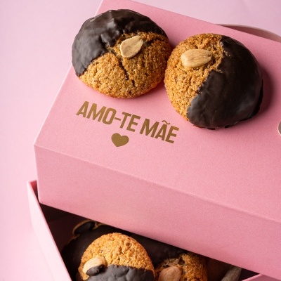 Caixa rosa com bolachas de amêndoa parcialmente cobertas de chocolate