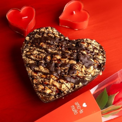 Coração de chocolate com nozes, velas de coração e embalagem com rosa e mensagem