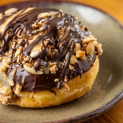 Donut com cobertura de chocolate e crumble num prato cerâmico