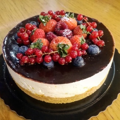 Bolo redondo com frutas vermelhas e mirtilos sobre prato preto