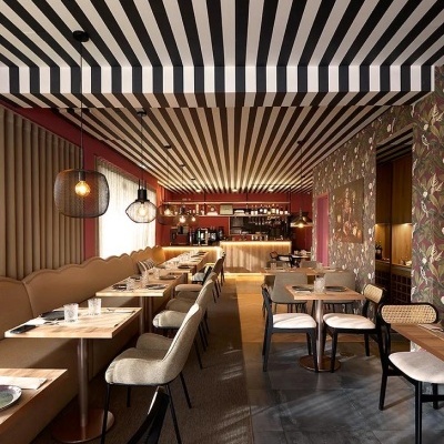 Interior de restaurante com teto de riscas pretas e brancas e decoração floral
