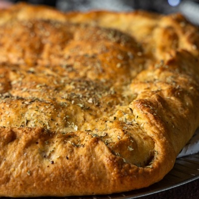 Massa assada dourada com ervas numa base metálica