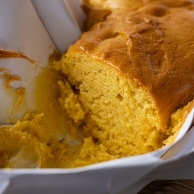 Bolo amarelo húmido cortado em forma com papel branco