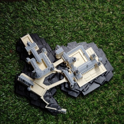 Maquete arquitetónica com estruturas cinza e bege sobre relva artificial