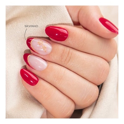 Unhas decoradas com verniz vermelho e nude com detalhes dourados em fundo creme