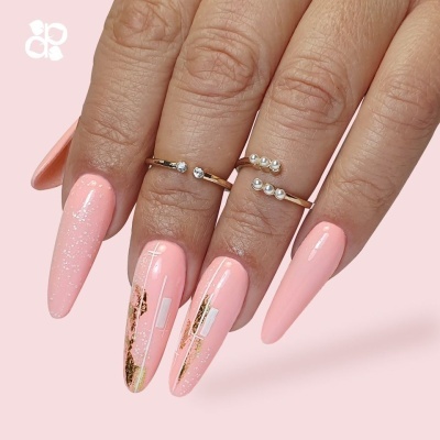 Unhas compridas rosa claro com decoração dourada e branca e anéis delicados