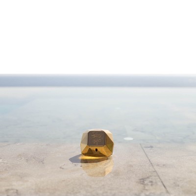 Embalagem dourada pequena sobre pedra junto a água clara