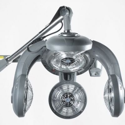 Lâmpada cirúrgica de três focos com estrutura metálica cinzenta e braço articulado numa parede branca