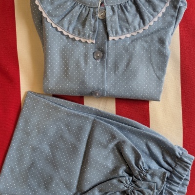 Pijama azul claro com pequenos pontos brancos e gola rodada branca.