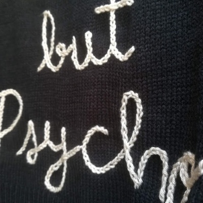 Detalhe de tecido de malha preta com bordado branco em relevo com texto