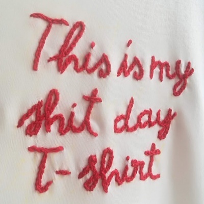 T-shirt branca com texto bordado em linha vermelha