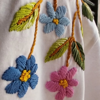 Tecido branco com bordados coloridos de flores e folhas