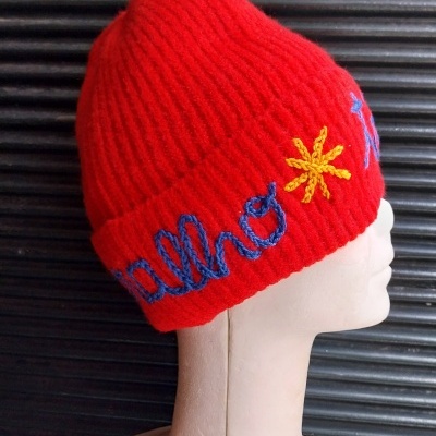 Gorro vermelho de malha com bordado azul e amarelo em manequim branco
