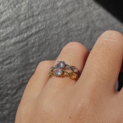 Anel dourado e prateado com pedras transparentes num dedo