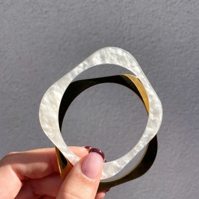 Pulseira quadrada bicolor de madrepérola branca e metal dourado.