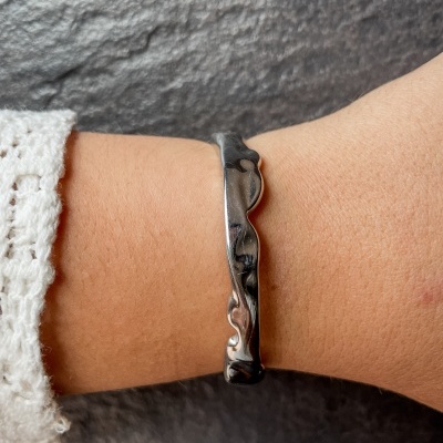 Pulseira prateada com design irregular no pulso