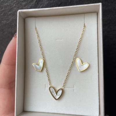 Conjunto de colar e brincos de coração em madrepérola e dourado em caixa de veludo branco.