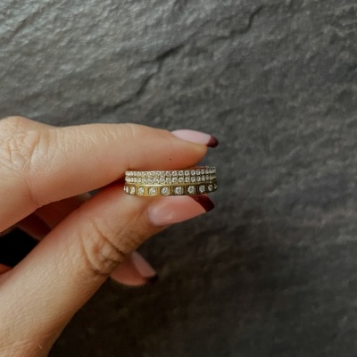 Anel de ouro com pedras brilhantes em fundo cinza