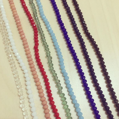 Fios de contas pequenas coloridas alinhados sobre superfície clara