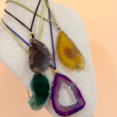 Colares com pendentes de ágata colorida em suporte de tecido bege