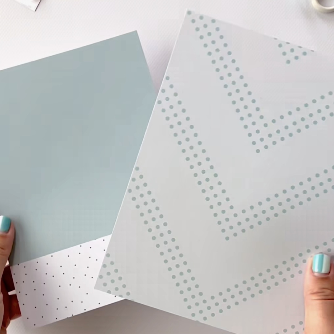 Dois cadernos com capas azuis e brancas com padrões de pontos segurados por mãos com unhas azul-claro