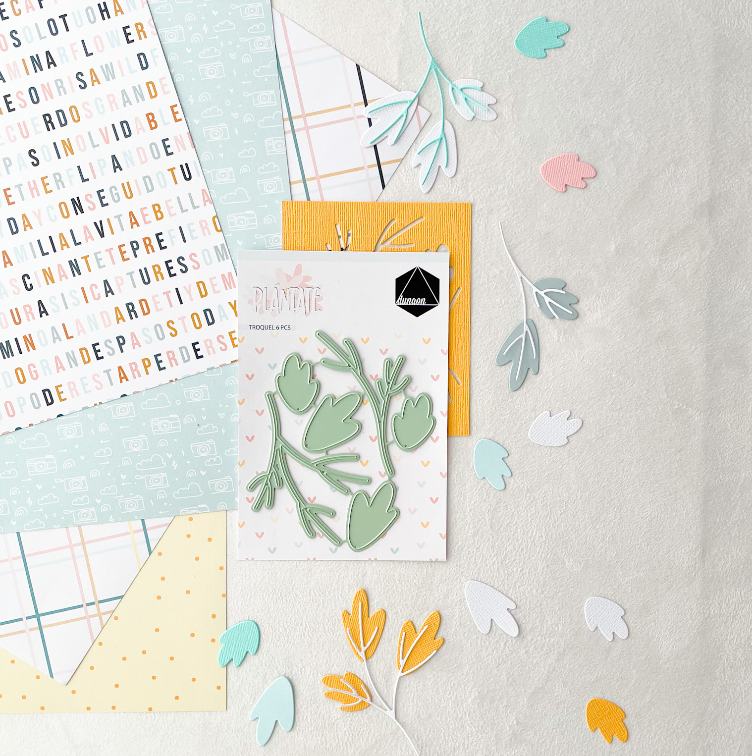 Conjunto de papéis decorativos e recortes de folhas coloridas sobre uma mesa clara